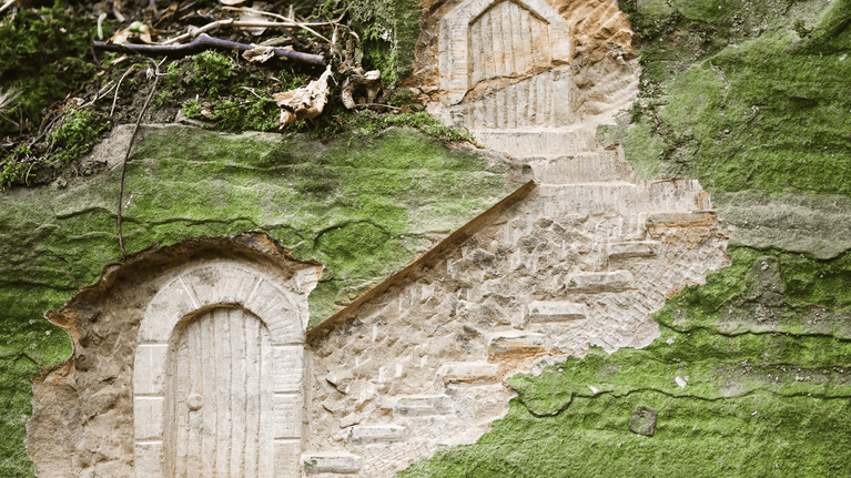 Two fairy doors carved into a mossy stone at Hardwick, Derbyshire